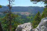 Au loin le cirque du Creux du Van. La Roche au Nom est au centre droite, à l'aplomb des bosquets sur le plateau